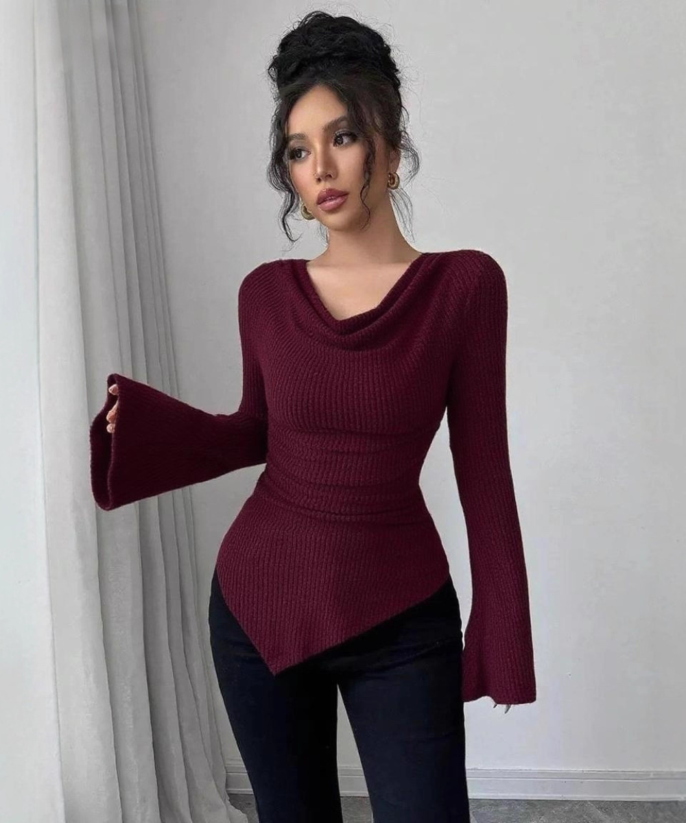 Woman wearing a burgundy ribbed sweater with bell sleeves against a neutral background