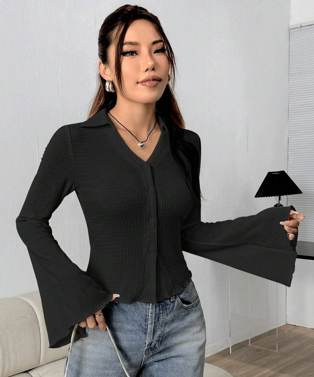 Woman wearing a black blouse and blue jeans in a room with a lamp and couch.