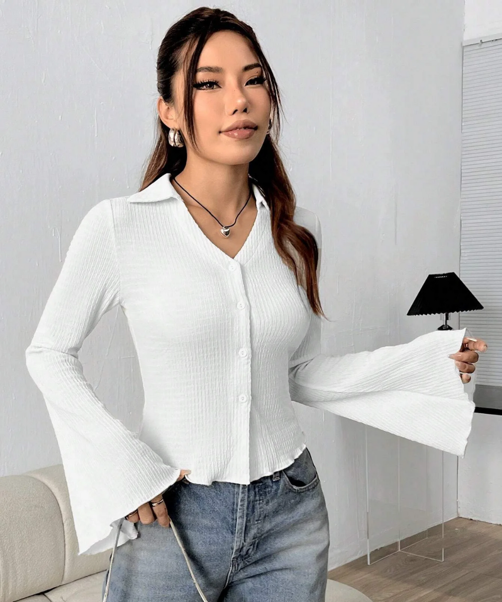 Woman wearing a white blouse and blue jeans indoors.