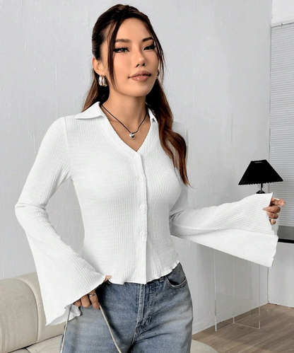 Woman wearing a white blouse and blue jeans indoors.