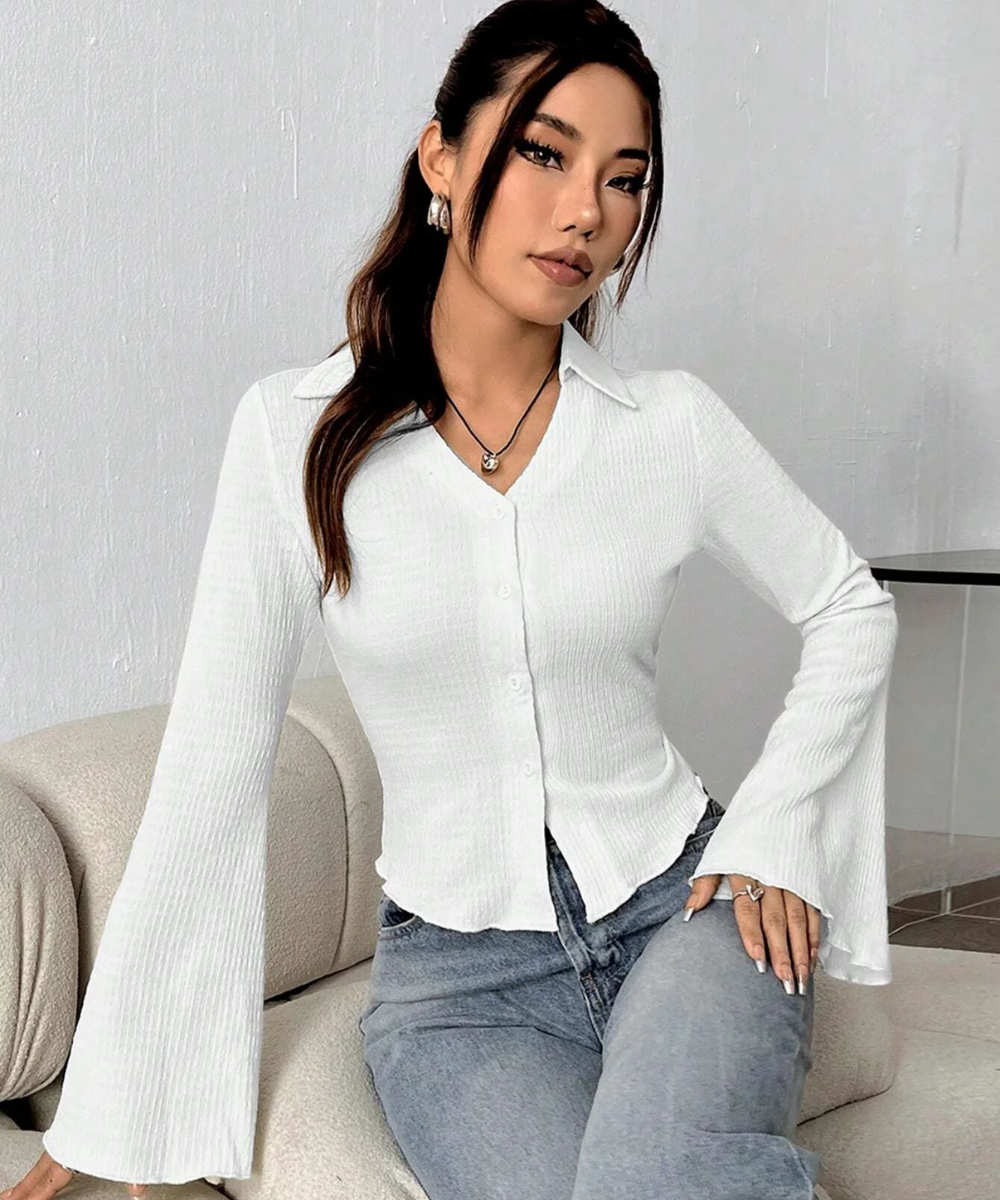 Woman wearing a white blouse and blue jeans sitting on a couch.