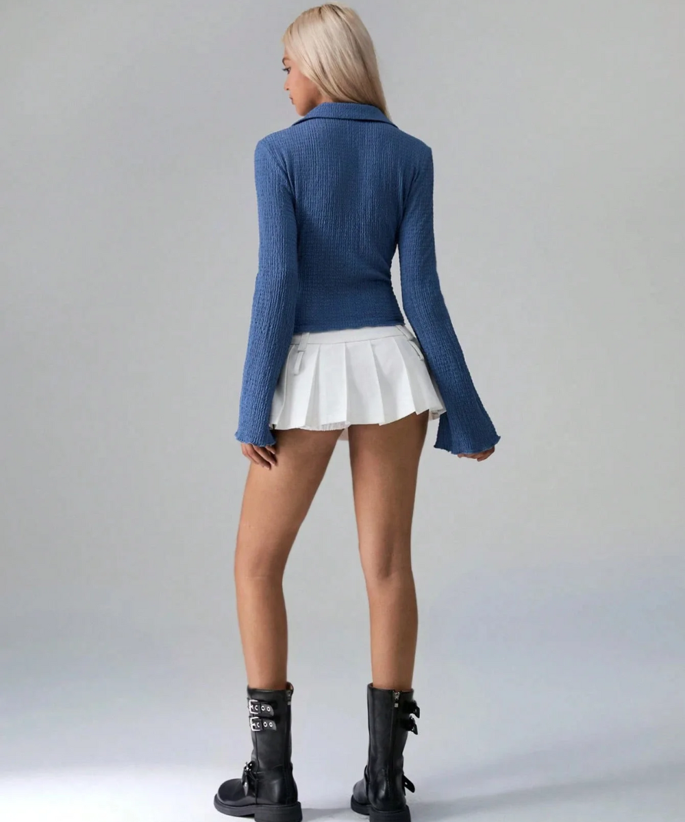 Person wearing a blue sweater and white skirt on a gray background